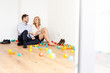 © Westend61 - Happy couple in business wear sitting on the floor surrounded by colorful balls