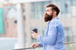Bearded man relax. brutal hipster with coffee cup. energy charge. Male barber care. copy space. Time zone. thoughtful man drink take away coffee outdoor. morning coffee. Mature hipster with beard