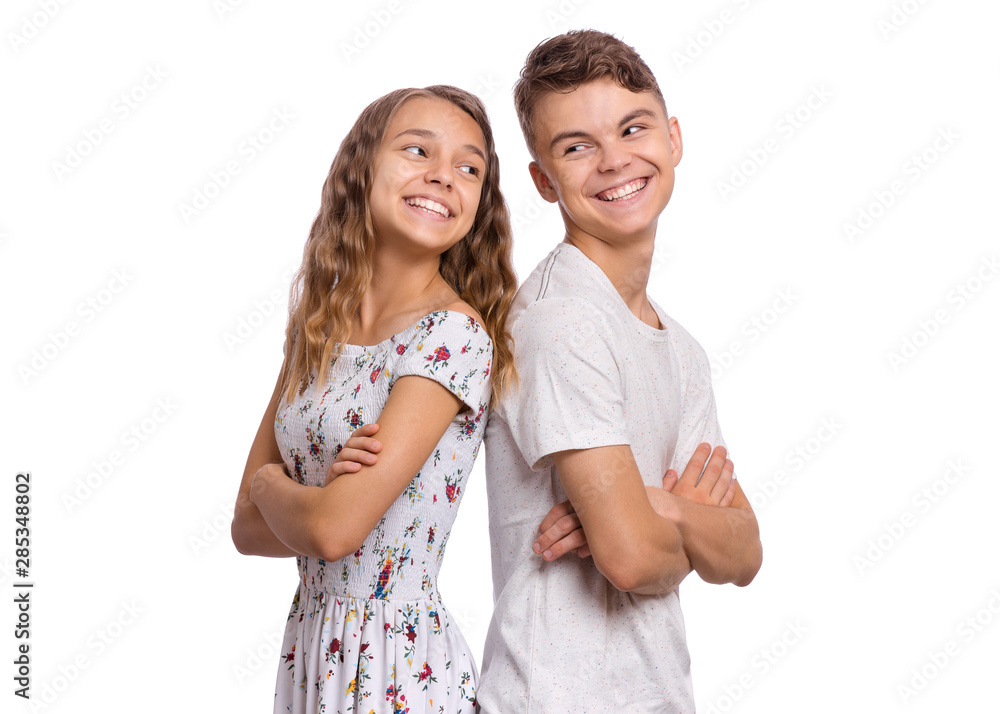 Portrait of smiling teen boy and girl standing back to back. Teenagers ...