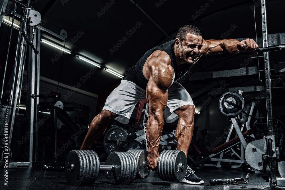 Hard Core Bodybuilding. Bodybuilder ready to lift heavy dumbbell - obrazy, fototapety, plakaty 