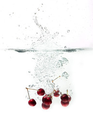 Canvas Print - fresh cherries falling in water on a white background