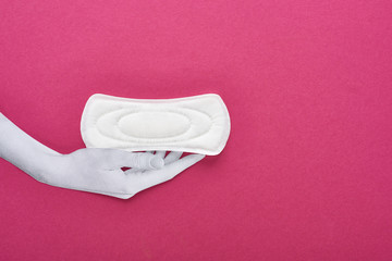 Wall Mural - top view of paper cut white hand and white sanitary napkin on purple background