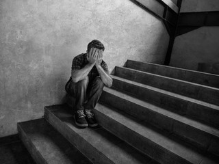 desperate man sitting outdoors on dark grunge street corner staircase feeling sick suffering depression problem and anxiety crisis in mental health concept