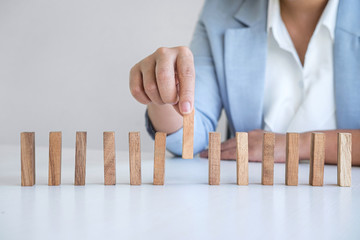 Risk and Strategy in Business, Image of hand gambling placing wooden block on a line of domino, prevention and development to stability