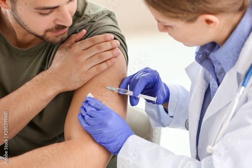 Cuadros en Lienzo Doctor vaccinating young man in clinic