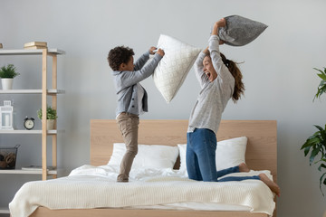 Wall Mural - Mixed ethnicity mum and son enjoy pillow fight on bed