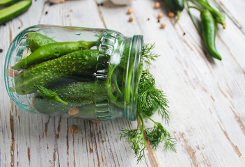 Fresh organic cucumbers pickles jar on white wooden table with green and red and chilli peppers,fennel,salt,black peppercorns,garlic,pea,green tomatoes,close up,healthy concept,top view,flat lay