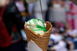 white ice cream in a waffle cone with flowing green syrup