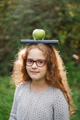 Wall Mural - Laughing girl with a book and apple on his head.