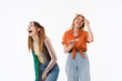 © Drobot Dean - Photo of two happy girls wearing colorful clothes laughing while holding smartphones together
