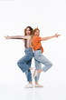 © Drobot Dean - Photo of two joyful girls wearing colorful clothes standing back to back and doing gun gesture with fingers