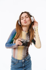 Sticker - Full length photo of beautiful young girl wearing headphones listening to music and carrying retro camera