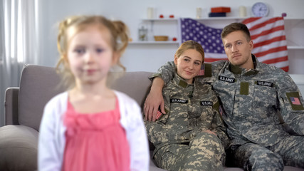 Wall Mural - Joyful parents in US military uniform admiring little daughter looking at camera