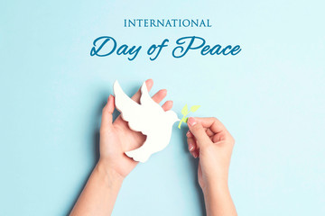 Wall Mural - World Peace Day greeting card. Female hands hold dove of peace with olive branch.