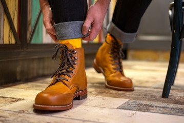 Man ordering his jeans and wearing yelloe brown brogues boots indoor, close up view