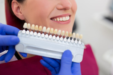 Wall Mural - close up of dentist checking the level of teeth whitening for young woman