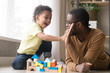© fizkes - African American father with toddler son playing with wooden constructor