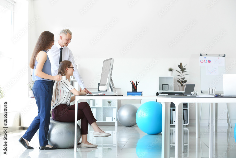 Young business people sitting on fitballs while working in office