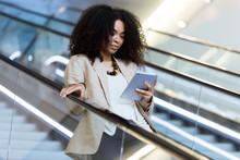 Young Businesswoman Using A Tablet On An Escalator