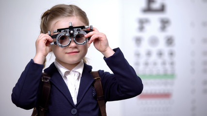 Poster - Schoolgirl putting optical trial frame to determine visual acuity, optometrist