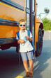 © anoushkatoronto - Funny cute happy Caucasian boy student kid with backpack and water bottle near yellow bus on 1 September day. Education and back to school concept. Child pupil ready to learn and study.