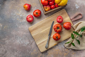 Cutting board with red tomatoes and knife, top view copy space