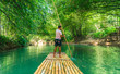 Man rowing bamboo raft, Martha Brae. Tourist boy whilst on cruise  on vacation in Montego Bay, Jamaica, Caribbean.