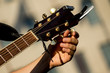 Man tuning acoustic guitar - only hand and neck of the guitar in sight - Selective focus