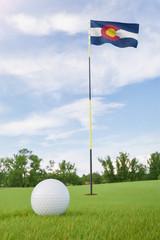 Wall Mural - Colorado flag on golf course putting green with a ball near the hole