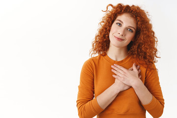 Your pleasant gift hit girls heart. Sensual gentle and tender curly-haired redhead woman hold hands on chest, tilt head smiling thankful, appreciate charming gesture, feel flattered and grateful