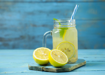 Lemonade or mojito cocktail with lemon and mint on wood background