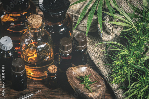 Fotografía CBD oil bottles and green plant of cannabis on a wooden background