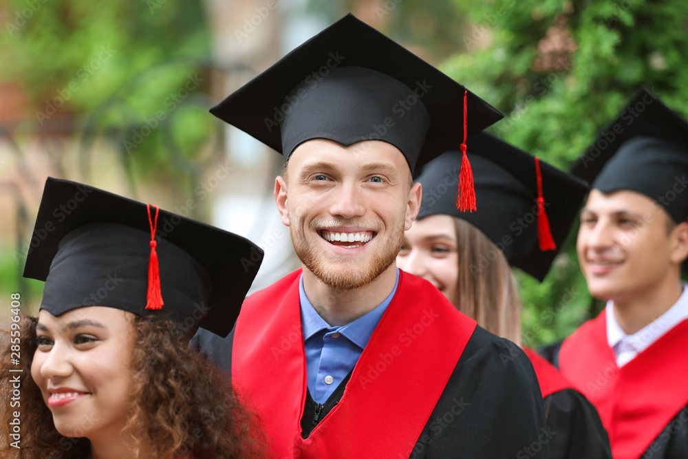Happy students in bachelor robes outdoors