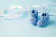 Blue Baby knitted shoes for newborns on blue background, Minimal baby shower, newborn party background, copy space