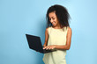 © Pixel-Shot - Portrait of beautiful African-American woman with laptop on color background