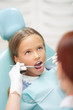 © zinkevych - Child dentist wearing white gloves examining girl