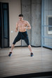 © KONSTANTIN SHISHKIN - An athletic man boxer in black shorts training in the bright studio