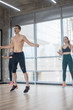 © KONSTANTIN SHISHKIN - Fitness training in the bright studio - two young women training with their coach - jumping exercises