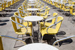 Small marble tables with bright yellow chairs bar in Piazza San Marco. St. Mark Square, Venice Italy