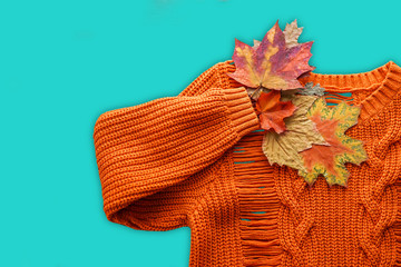 Wall Mural - Orange sweater and autumn leaves isoalted over blue. Minimal style, flat lay