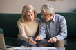 © fizkes - Serious stressed old couple looking at calculator feeling worried