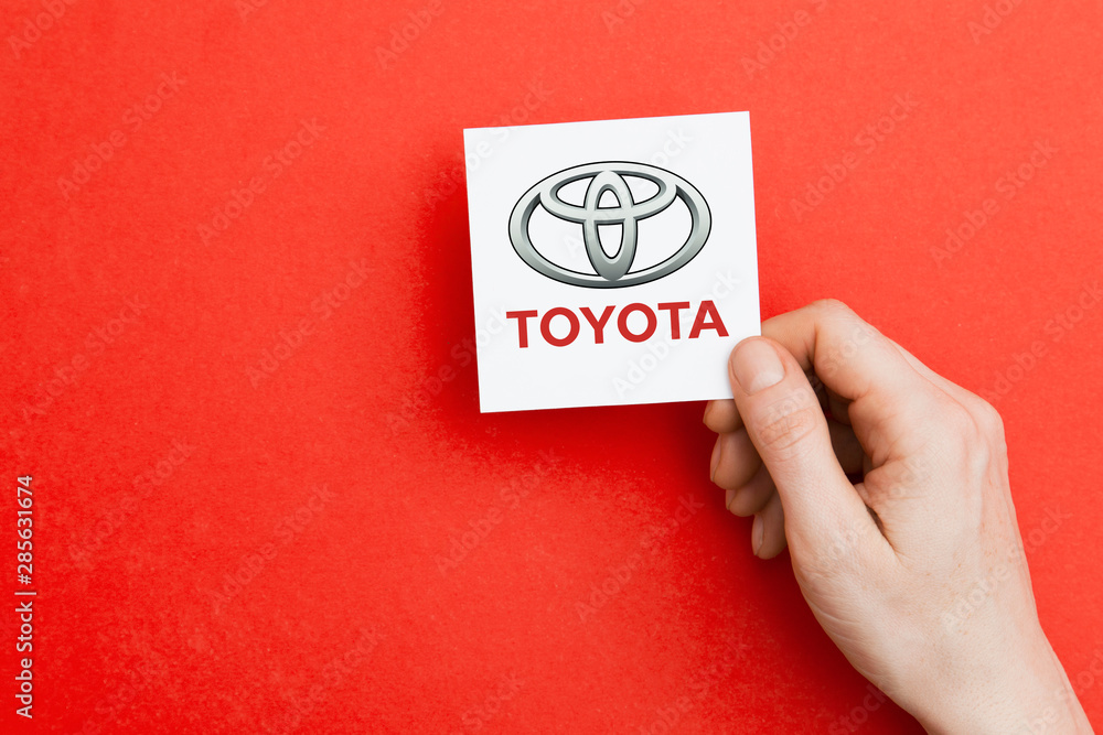 LONDON, UK - October 26th 2018: Hand holding a Toyota logo. Toyota is an automobile manufacturer.