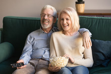 Happy Senior Couple Holding Remote Control Snack Laughing Watching Tv