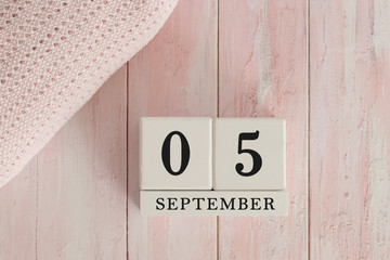 5 September Date on Cubes. Date on painted pink wood, next to baby blanket. Theme of baby due dates and birth dates.