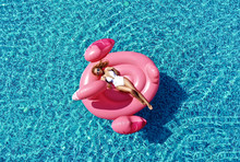 Beautiful  Sexy Woman Inflatable Giant Pink Flamingo Float Mattress In Blue Swimming Pool With Text Space. Summer Vibes Tourist