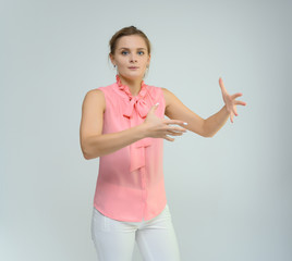 Photo studio portrait of a cute young woman girl in a beautiful suit of white-pink tender color on a white background. He stands right in front of the camera, explains with emotion.