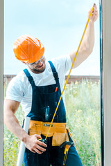 Wall Mural - selective focus of happy repairman measuring window with yellow measuring tape