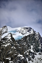 Wall Mural - large glacier in winter on top of a mountain in the alps full of snow and ice under a cloudy sky