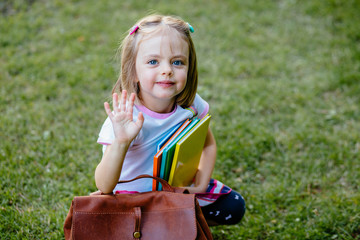 Full size body length of cute cheerful lovely stylish adorable small little girl with curly ponytails in blouse shirt and blue skirt, keeping color book pile, folders.