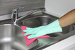 Hands in protective gloves with rag wiping sink. Maid or housewife cleans house. General cleaning or regular wash up.